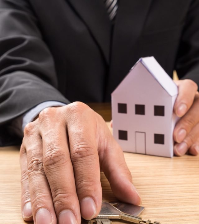 Real estate agent with house model and keys.